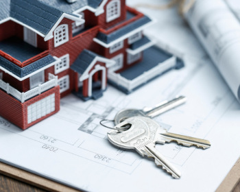 Villa house model, key and drawing on retro desktop (real estate sale concept)